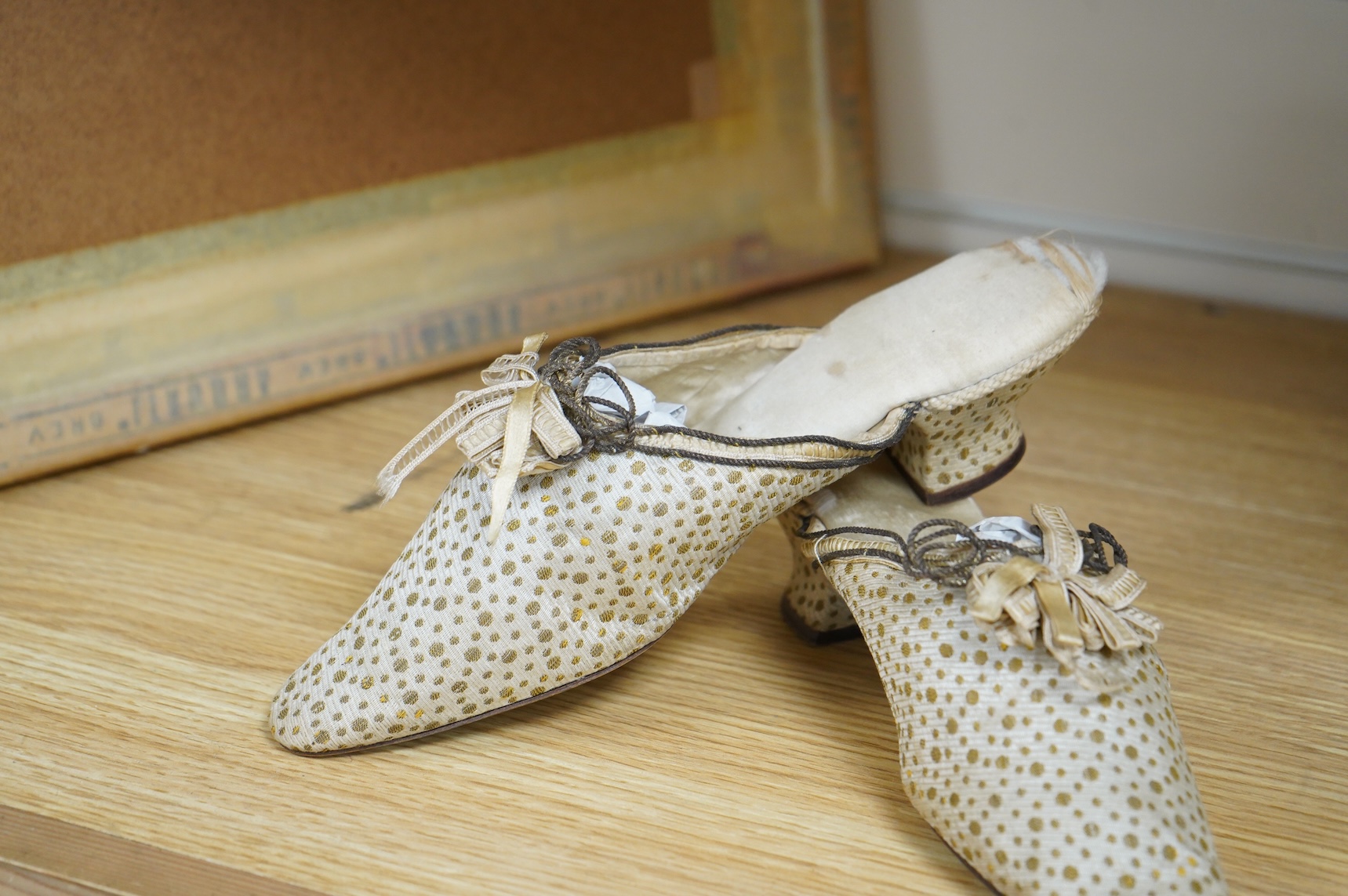 Of interest to collectors and costume designers: a pair of late 19th / early 20th century ladies gold spot embroidered mules, decorated at the front with a rosette of silk ribboning and fine cording. Condition - the cord